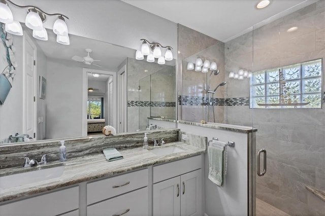 bathroom with a shower with door, ceiling fan, and dual bowl vanity