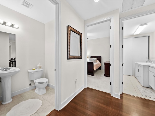 bathroom featuring separate washer and dryer, hardwood / wood-style flooring, and toilet