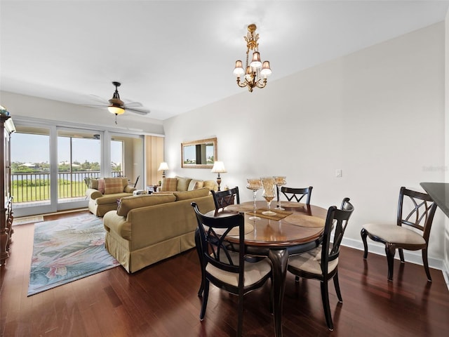 dining room with ceiling fan with notable chandelier and dark hardwood / wood-style floors