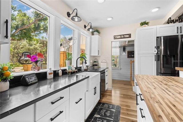 kitchen with light hardwood / wood-style floors, stainless steel fridge, white cabinets, and wood counters