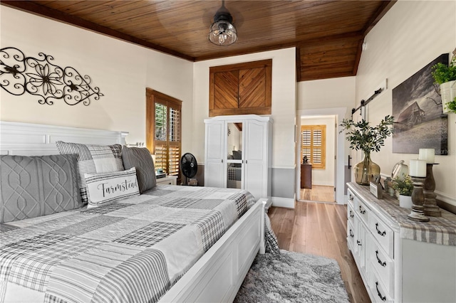 bedroom featuring a barn door, light hardwood / wood-style flooring, and wood ceiling