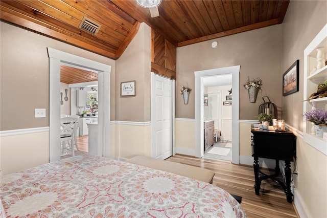 bedroom featuring ceiling fan, ensuite bathroom, light wood-type flooring, and wood ceiling