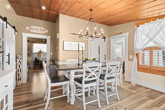 dining room with a barn door, light hardwood / wood-style flooring, a wealth of natural light, and wood ceiling