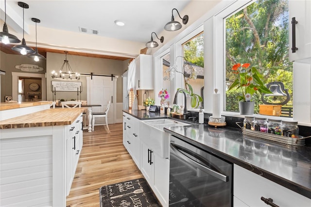 kitchen featuring a barn door, white cabinets, dishwasher, and hanging light fixtures