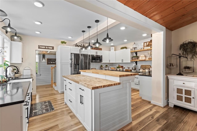 kitchen with butcher block counters, light wood-type flooring, a kitchen island, appliances with stainless steel finishes, and white cabinets