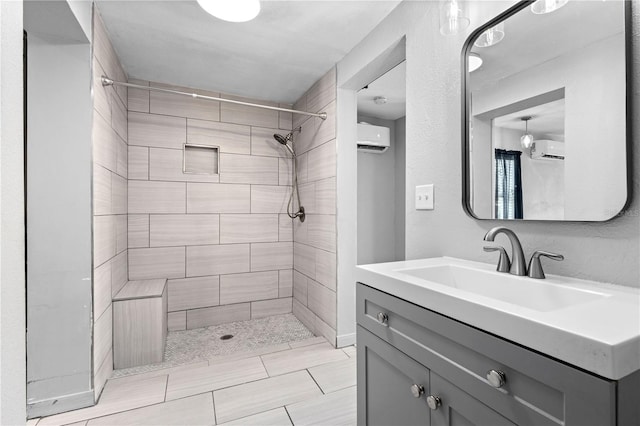 bathroom with tiled shower, a wall mounted AC, and vanity