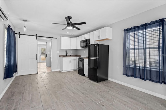 kitchen with white cabinetry, black appliances, a barn door, sink, and ceiling fan