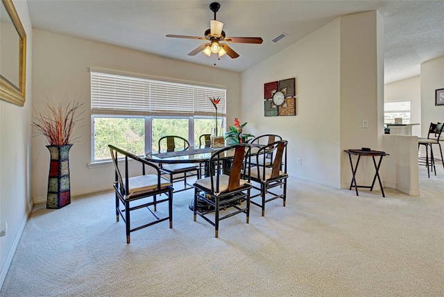 dining space featuring ceiling fan, vaulted ceiling, and light colored carpet