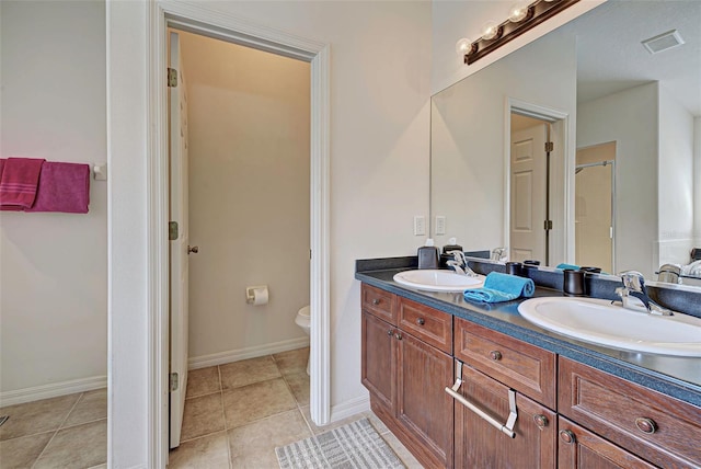 bathroom featuring tile floors, oversized vanity, toilet, and double sink