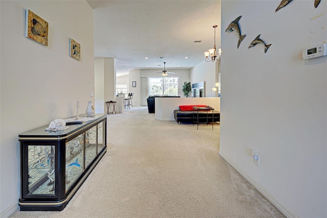 hall with a notable chandelier and carpet flooring