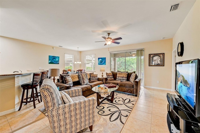 living room featuring ceiling fan, light tile floors, and a wealth of natural light