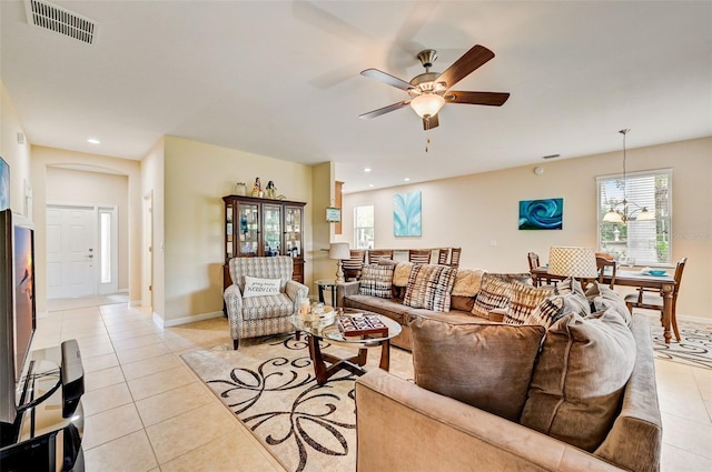 living room with ceiling fan with notable chandelier and light tile floors