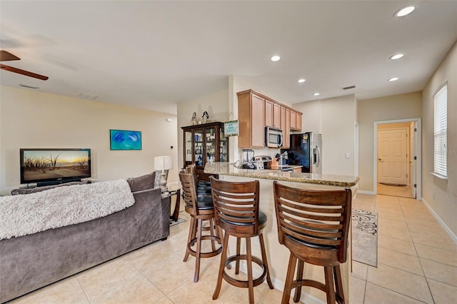 kitchen with kitchen peninsula, stainless steel appliances, ceiling fan, and light tile floors