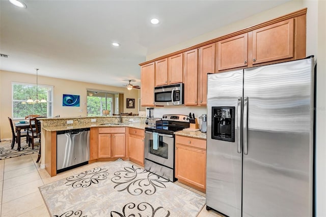 kitchen with decorative light fixtures, light stone countertops, light tile flooring, kitchen peninsula, and appliances with stainless steel finishes