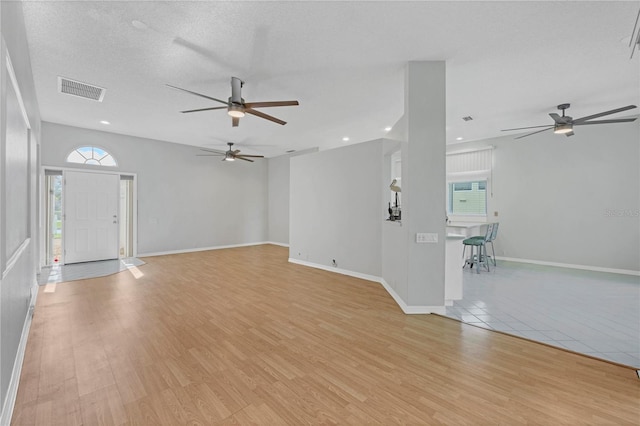 unfurnished living room with light hardwood / wood-style flooring and a textured ceiling