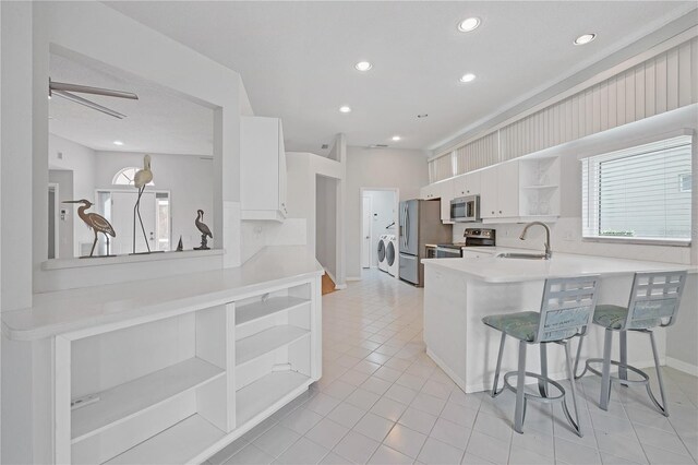 kitchen featuring kitchen peninsula, a kitchen breakfast bar, stainless steel appliances, sink, and white cabinets