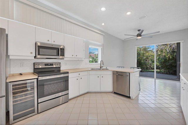 kitchen with a healthy amount of sunlight, sink, stainless steel appliances, and beverage cooler