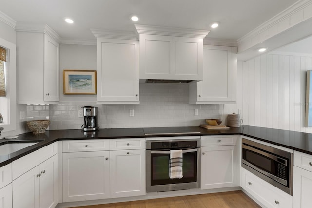 kitchen with white cabinets, appliances with stainless steel finishes, light hardwood / wood-style flooring, and tasteful backsplash