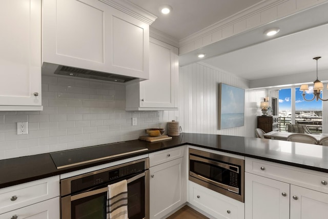 kitchen featuring tasteful backsplash, pendant lighting, a notable chandelier, white cabinetry, and appliances with stainless steel finishes