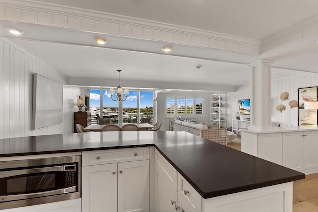 kitchen featuring white cabinetry, light hardwood / wood-style floors, stainless steel microwave, decorative light fixtures, and a notable chandelier