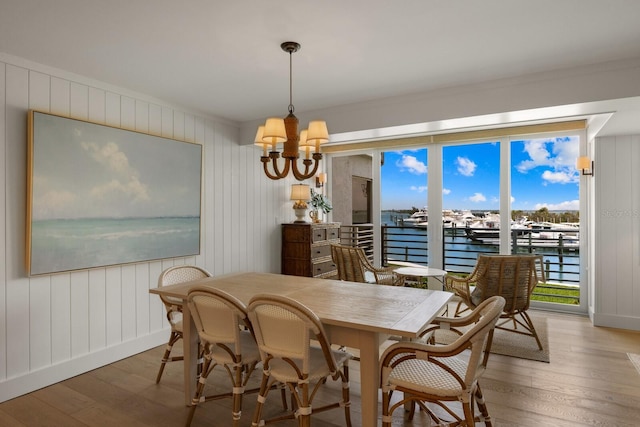 dining area with a notable chandelier, a water view, ornamental molding, and hardwood / wood-style flooring