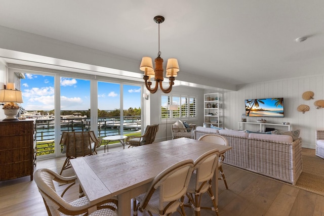 dining space featuring a water view, a chandelier, and hardwood / wood-style flooring