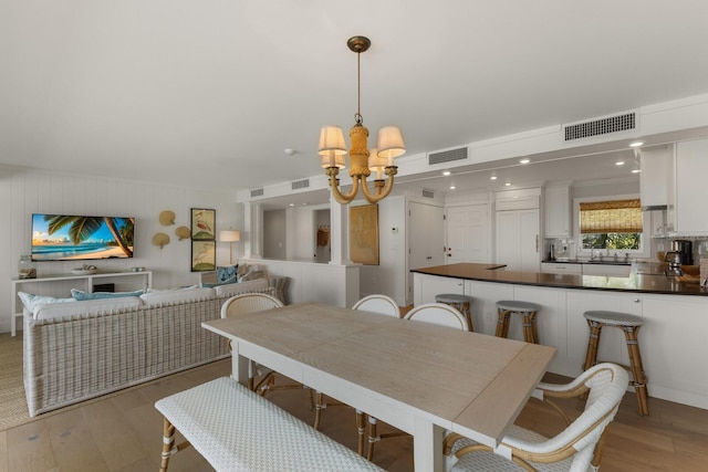 dining space with sink, light hardwood / wood-style floors, and a chandelier