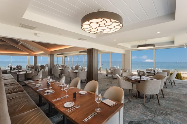 dining area featuring a water view and a tray ceiling