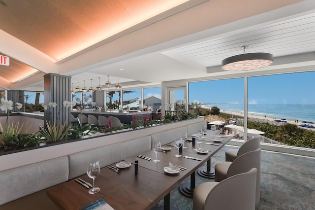 dining room featuring beamed ceiling, a beach view, and a water view