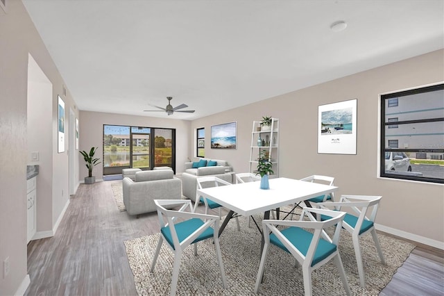 dining space featuring wood-type flooring and ceiling fan