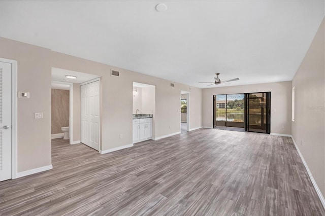 unfurnished living room featuring sink, hardwood / wood-style flooring, and ceiling fan