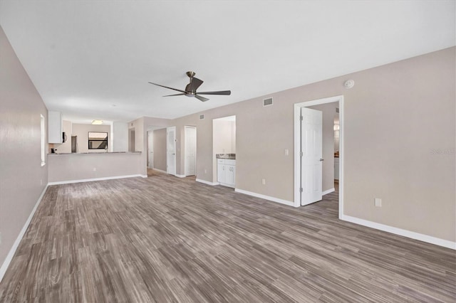 unfurnished living room featuring dark hardwood / wood-style flooring and ceiling fan