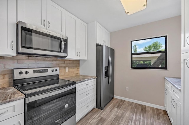 kitchen with light hardwood / wood-style floors, light stone countertops, white cabinetry, stainless steel appliances, and backsplash