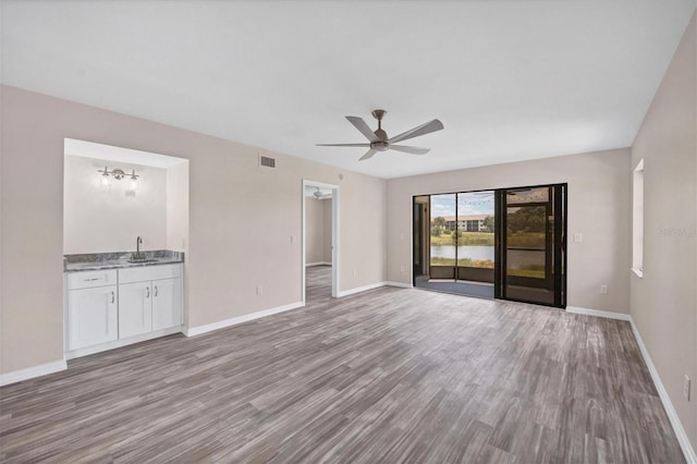 unfurnished living room with hardwood / wood-style floors, sink, and ceiling fan