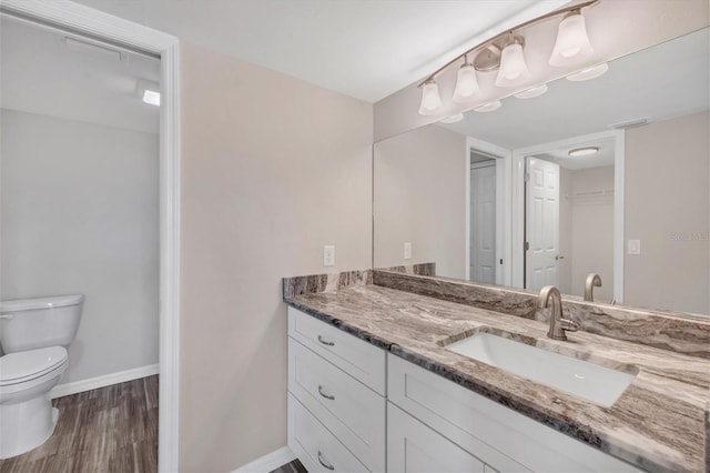 bathroom with wood-type flooring, vanity, and toilet