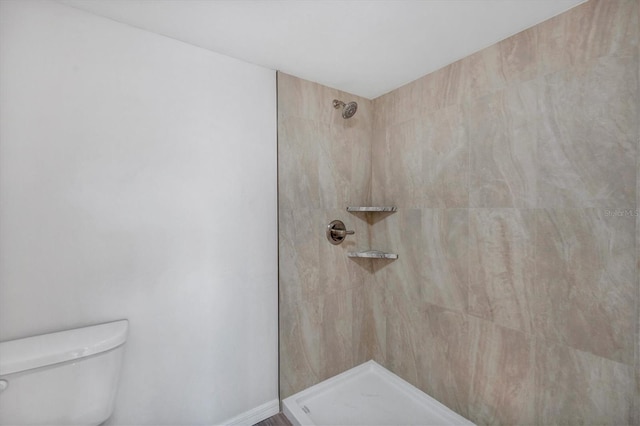 bathroom featuring a tile shower and toilet