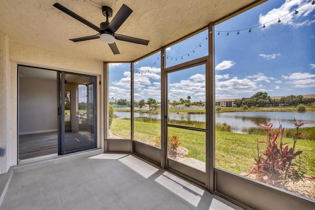 unfurnished sunroom with ceiling fan, a healthy amount of sunlight, and a water view