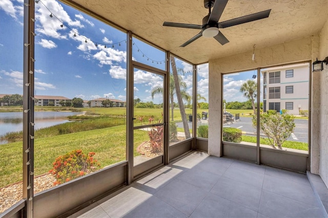 unfurnished sunroom with ceiling fan and a water view