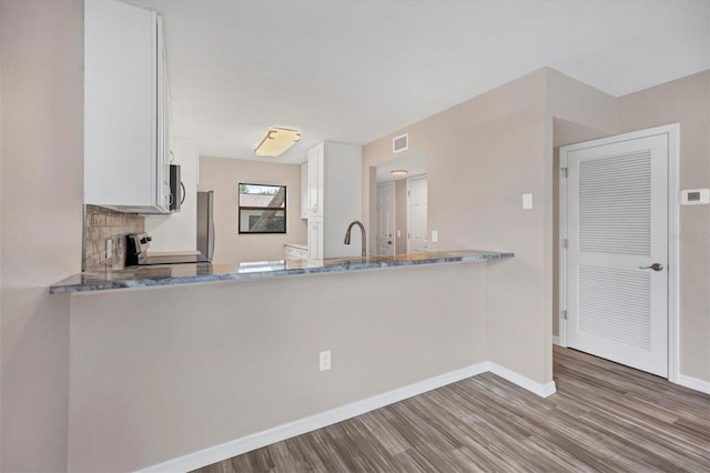 kitchen with light stone counters, white cabinetry, wood-type flooring, and range