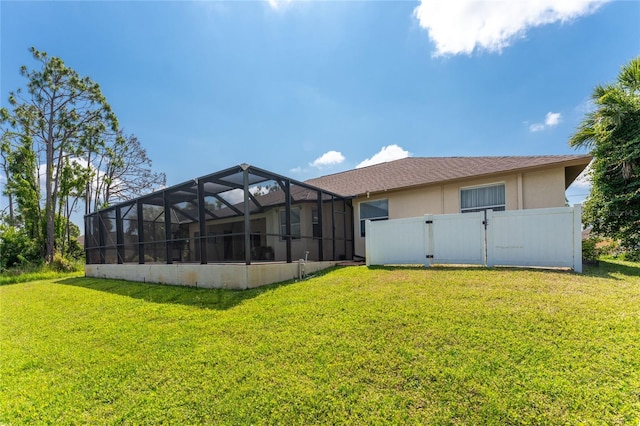 rear view of house featuring a lawn and glass enclosure