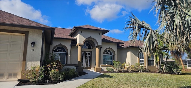 mediterranean / spanish-style home featuring a garage and a front lawn