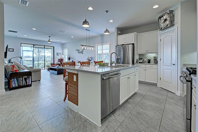 kitchen with appliances with stainless steel finishes, a wealth of natural light, pendant lighting, and an island with sink