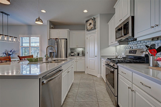 kitchen featuring appliances with stainless steel finishes, a kitchen island with sink, sink, backsplash, and pendant lighting