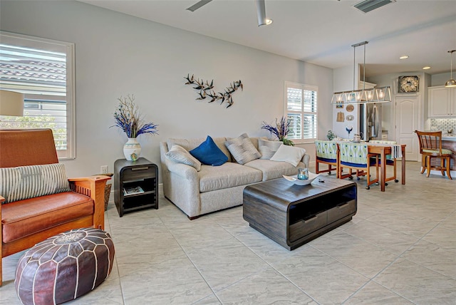 living room featuring ceiling fan with notable chandelier and light tile flooring