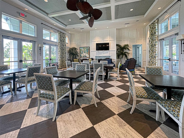 dining area with french doors, ceiling fan, a towering ceiling, and coffered ceiling