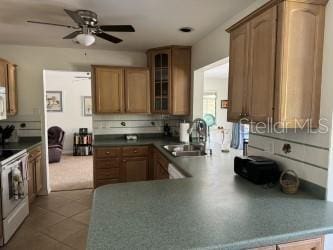 kitchen with sink, white appliances, light tile patterned floors, and kitchen peninsula