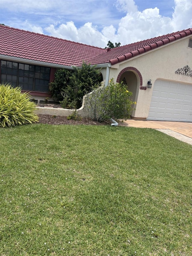 mediterranean / spanish-style home with a front yard and a garage