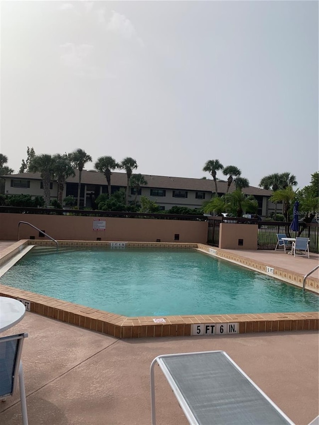 community pool with fence and a patio