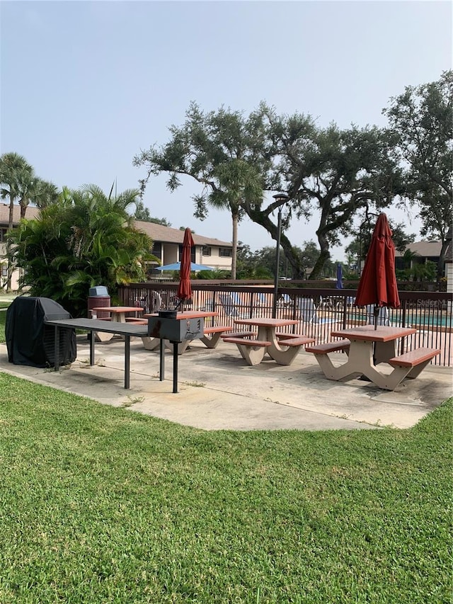 view of playground featuring a lawn, a patio, and fence