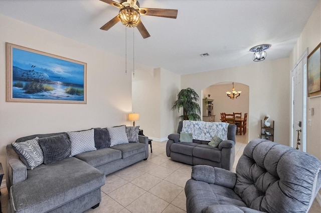 tiled living room with ceiling fan with notable chandelier